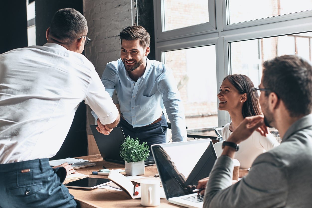 Colleagues shaking hands around a conference table